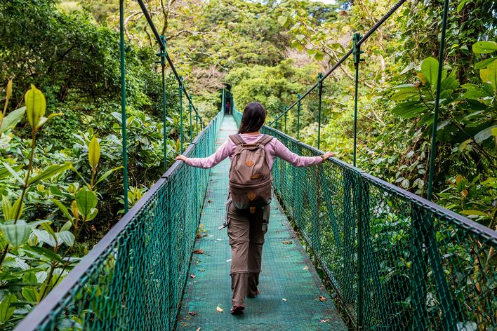 Frau auf Hängeseilbrücke im Nebelwald Monteverde