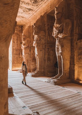 Touristin steht vor den monumentalen Statuen im Tempel von Abu Simbel in Ägypten