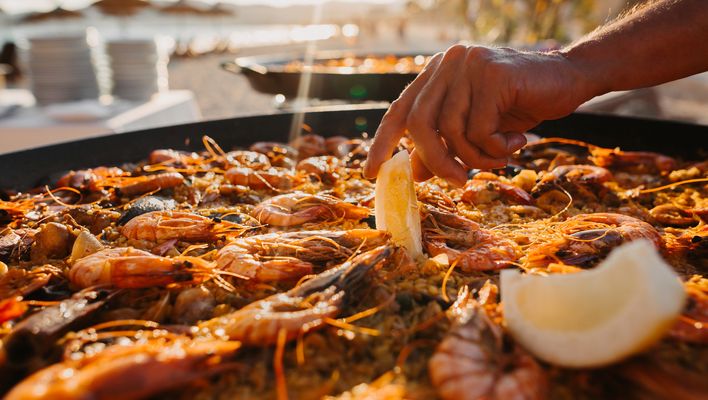 Eine Paella mit Reis, Meeresfrüchten und Gemüse wird frisch aus einer großen Pfanne auf Mallorca serviert