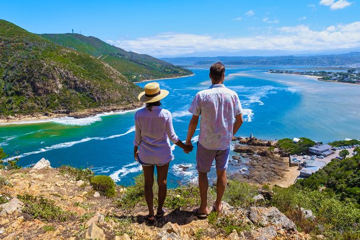 Zwei Reisende genießen gemeinsam das Panorama über die türkisfarbene Lagune von Knysna in Südafrika