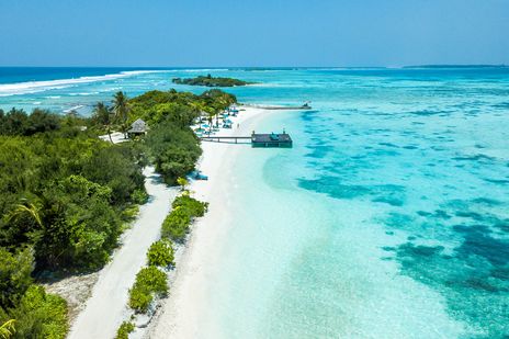 Blick auf eine Malediven-Insel mit Lagune, Booten und Korallenriffen