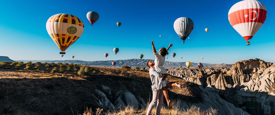Paar mit Heißluftballons in Kappadokien