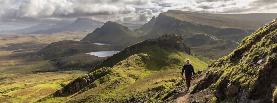 Person beim Wandern durch die Hügellandschaft auf der Isle of Skye