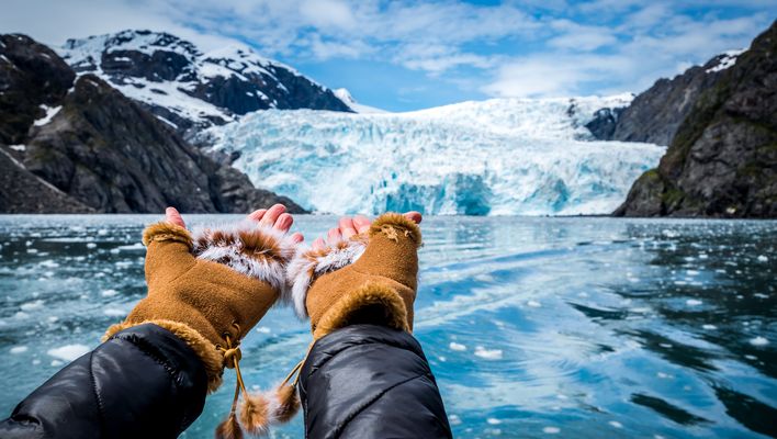 Hände zeigen auf eine Eiswand eines Gletschers mit blauem Eis in Alaska