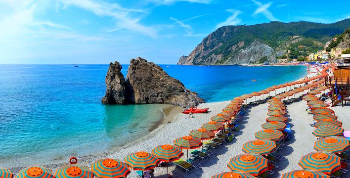 Strand in Cinque Terre mit bunten Sonnenschirmen und Küstenblick