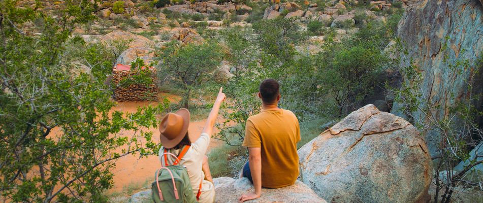 Ein Paar sitzt auf einem Felsen in der wüste Namib und beobachtet die Gegend