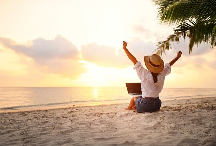 Frau am Strand mit einem Laptop auf den Beinen