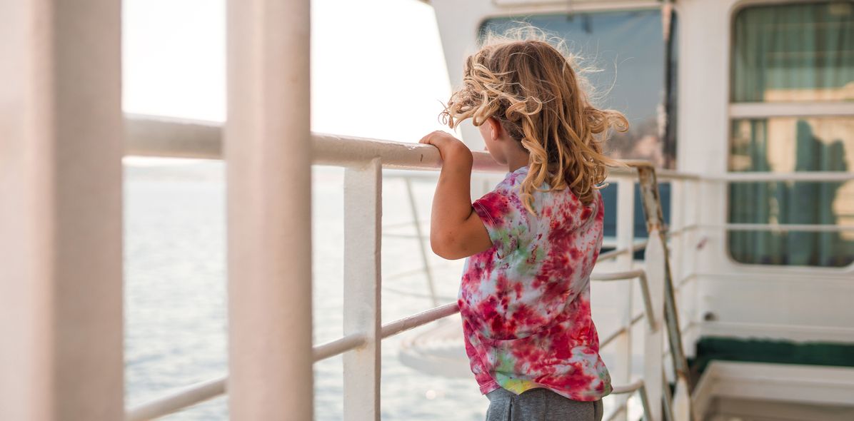 Ein Kind blickt vom Schiff hinaus aufs Meer