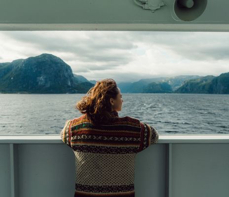 Frau genießt den Ausblick auf das Meer und die Landschaft bei einer Kreuzfahrt