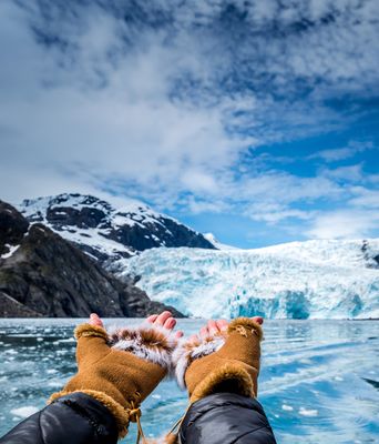 Hände zeigen auf eine Eiswand eines Gletschers mit blauem Eis in Alaska