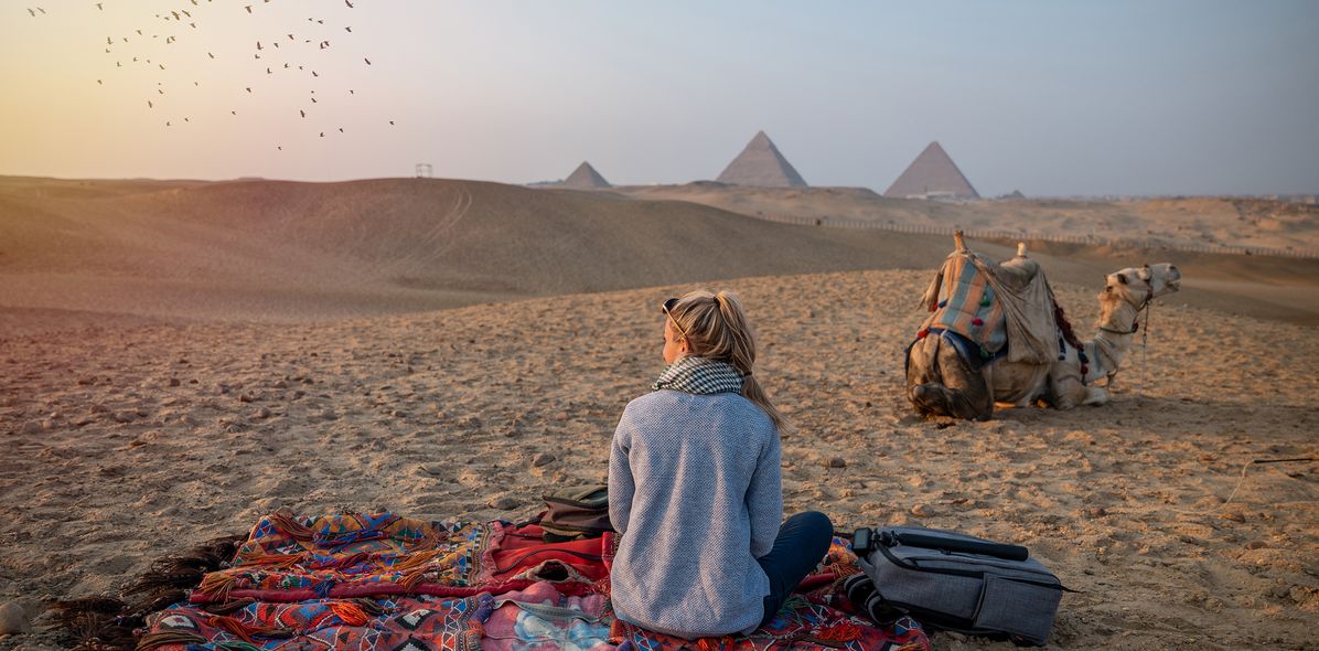 Frau und Kamel sitzen in Wüste