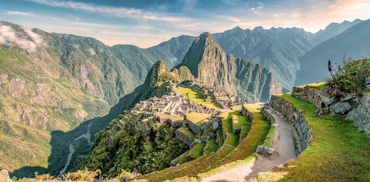 Panoramablick auf Machu Picchu mit Serpentinenweg und grünen Berghängen