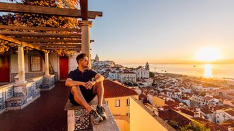 Mann genießt bei einem Sonnenuntergang den Blick auf die Stadt Lissabon