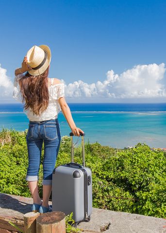 Frau am Strand mit Handgepäckskoffer
