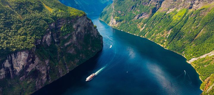 Ein Kreuzfahrtschiff von oben fotografiert ist unterwegs im berühmten Geiranger-Fjord in Norwegen
