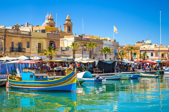 Markt an der Promenade von Marsaxlokk mit bunten Booten im Vordergrund auf der Insel Malta