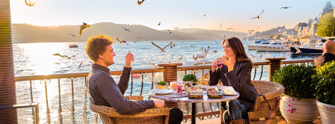 Paar sitzt in einem Restaurant am Bosporus in Istanbul mit Blick auf die Skyline