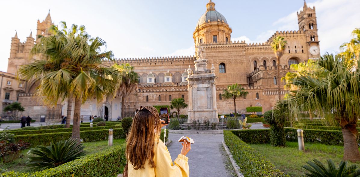 Frau vor der Kathedrale von Palermo mit Palmen und Platz