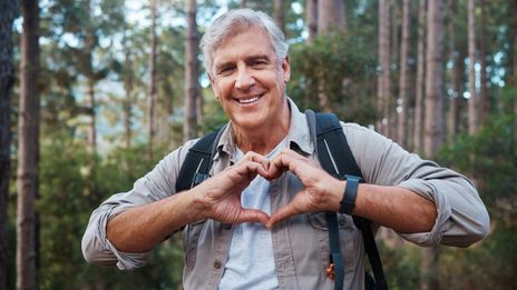 Mann beim wandern zeigt Herz mit Händen