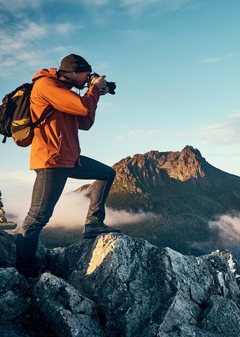 Mann beim Fotografieren auf einem Berg