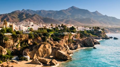 Felsige Küstenlinie bei Nerja mit türkisblauem Wasser und Bergkulisse im Hintergrund