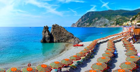 Strand in Cinque Terre mit bunten Sonnenschirmen und Küstenblick