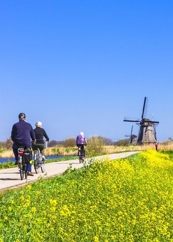 Radfahrer entlang eines Kanals mit Windmühlen in den Niederlanden