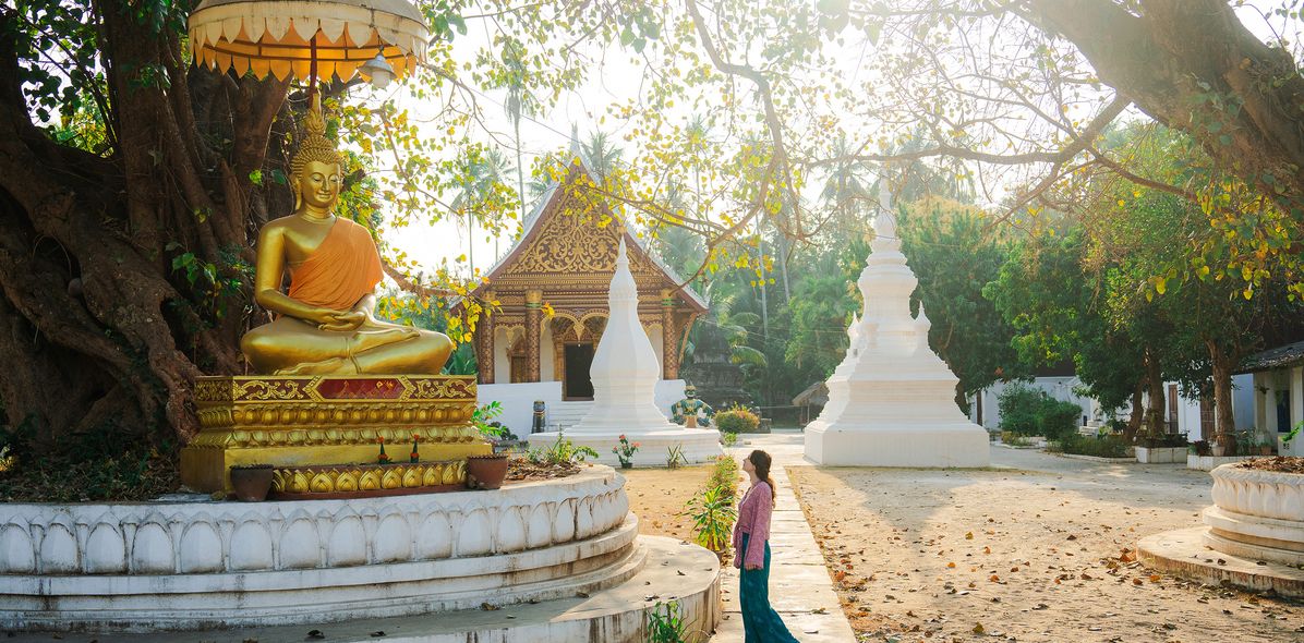 Frau steht vor einer Buddha Statue in Luang Prabang, Laos