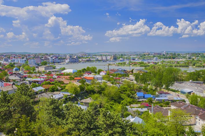 Tulcea breitet sich mit grünen Vierteln und roten Dächern unter einem weiten Wolkenhimmel aus.