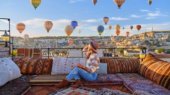 Reisende sitzen auf einer Terrasse und frühstücken mit Blick auf Ballons