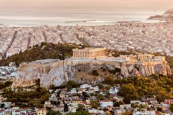 Luftaufnahme von der Akropolis aus der Ferne mit den Häusern von Athen und dem Meer im Hintergrund