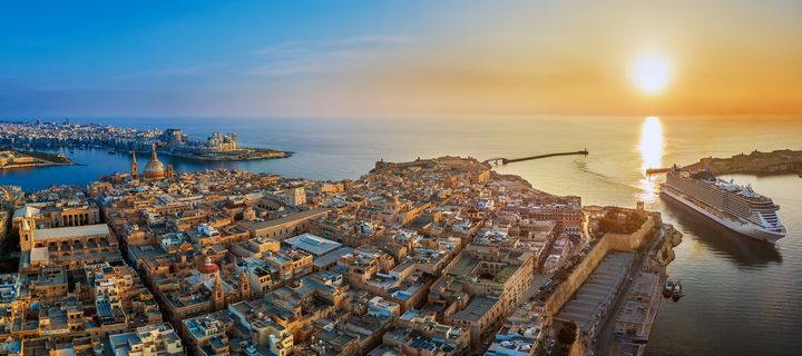 Blick über den Hafen von Valletta mit Kreuzfahrtschiff und Sonnenuntergang auf Malta