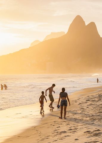 Menschen am Ipanema Beach in Rio de Janeiro bei Sonnenuntergang