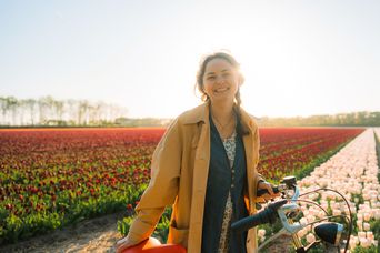 Frau mit Fahrrad vor Tulpenfeld