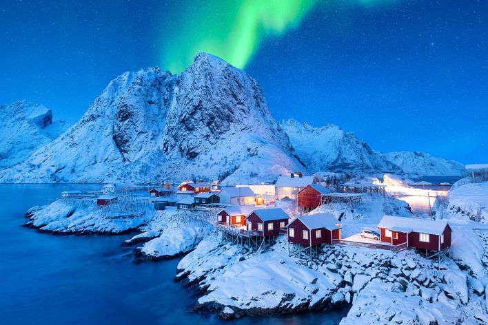Ein Fischerdorf in den Lotofen in einer Schneelandschaft mit Nordlichtern am Himmel