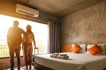 Paar steht Hand in Hand im Hotelzimmer und blickt durch das Fenster