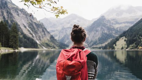 Frau steht an einem Bergsee beim wandern