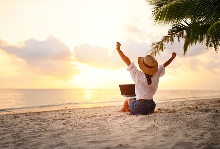 Frau am Strand mit einem Laptop auf den Beinen