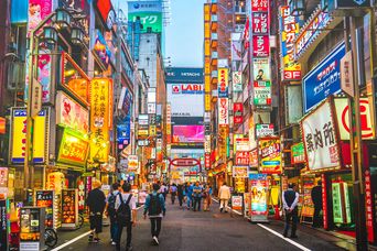 Straße in Tokio mit bunten Schildern und Menschen