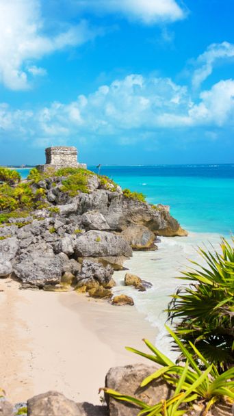 Felsige Bucht bei Tulum mit weißem Sand, Palmen und klarem Karibikmeer