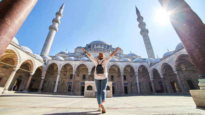 Frau steht im Innenhof einer Moschee in Istanbul mit Blick auf Kuppeln