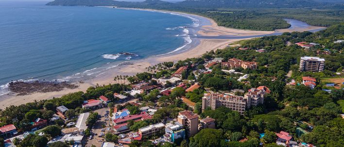 Luftaufnahme der Küstenstadt Tamarindo in Costa Rica mit Strand, Wellen und grüner Umgebung