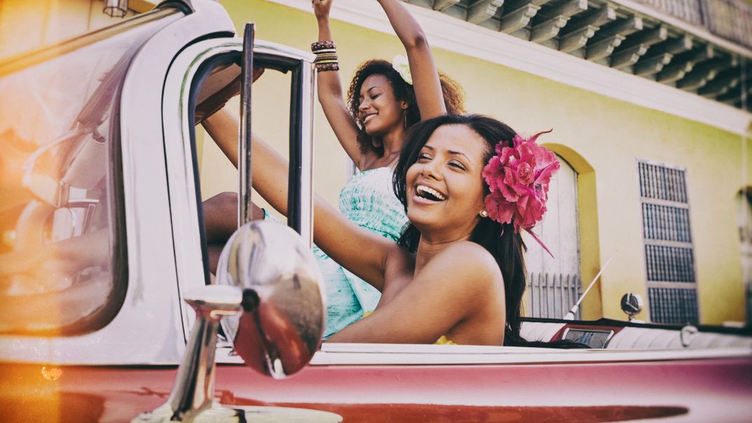 Lachende kubanische Frauen sitzen feiernd in einem Oldtimer
