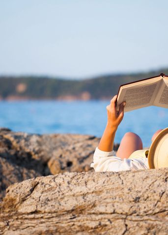 Frau liest Buch am Meer