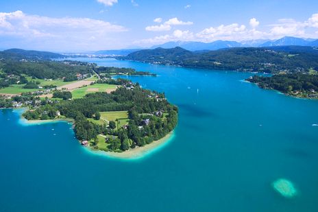 Luftaufnahme des Wörthersees mit türkisblauem Wasser und grüner Uferlandschaft