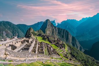 Machu Picchu im Abendlicht mit tiefem Tal und umliegenden Andenbergen