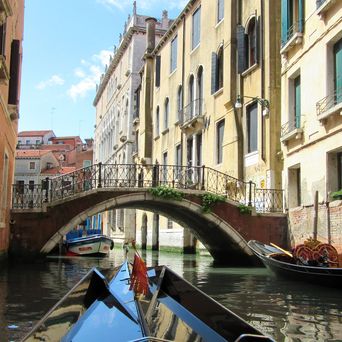 Eine Gondelfahrt durch Venedig unter niedrigen Brücken hindurch, Italien