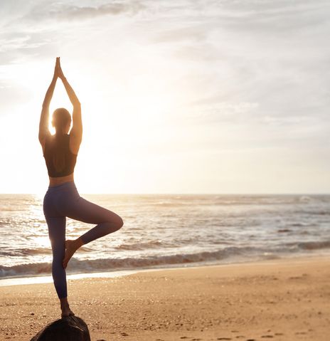 Frau macht Yoga am Strand