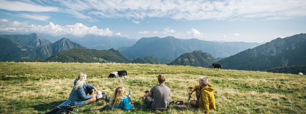 Gruppe liegt nach einer Wanderung auf der Wiese in den Bergen