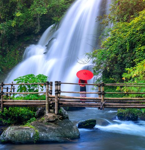 Eine Frau vor einem Wasserfall in der Region Chiang Mai
